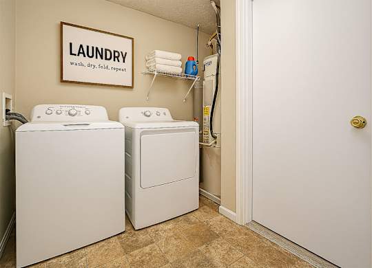 A laundry sign hangs on a wall above a washer and dryer.