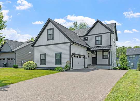A large house with a grey roof and a driveway in front.