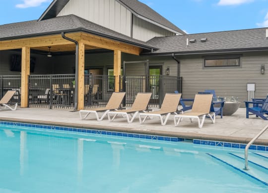 a swimming pool with chaise lounge chairs and a building in the background