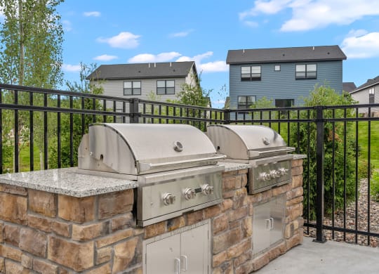 an outdoor kitchen with two bbq grills and a granite countertop