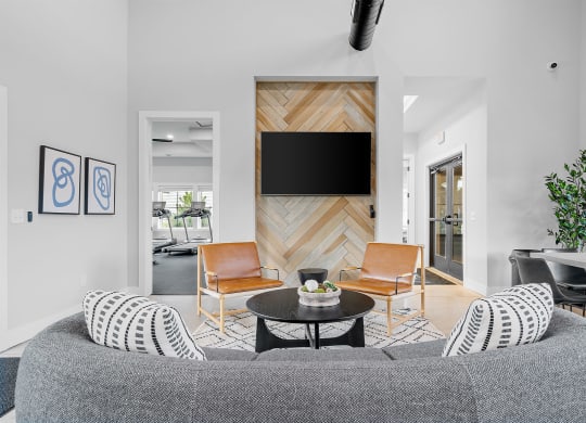 a living room with a gray couch and two orange chairs