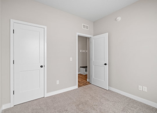 a bedroom with two doors and a carpeted floor