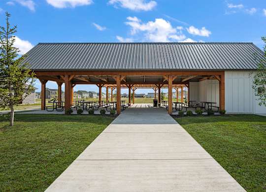 A pavement leads to a pavilion with a white building and a black roof.
