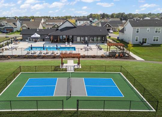 A tennis court is surrounded by a fence and a pool.