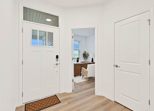 A white door with a glass window is open to a room with a desk and a chair.