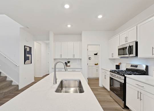A modern kitchen with white cabinets and stainless steel appliances.