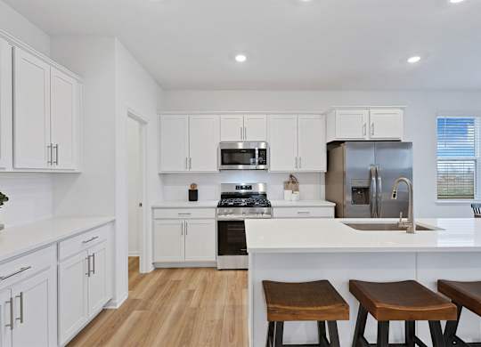 A kitchen with white cabinets and a wooden floor.