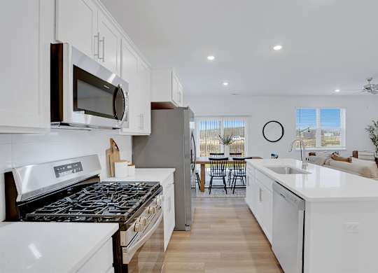 A modern kitchen with white cabinets and a black stove top.
