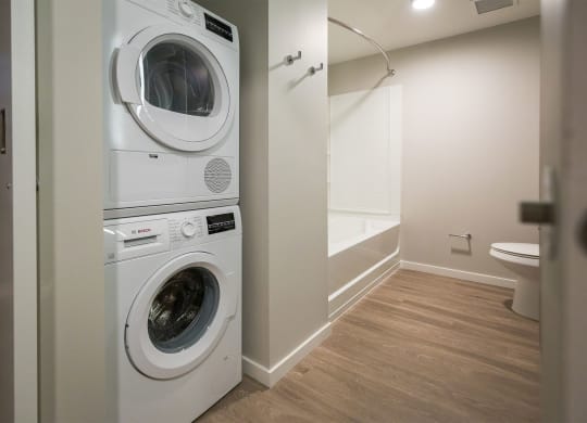 a washer and dryer in a laundry room with a tub and a toilet