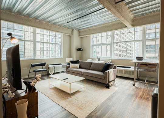 a living room with a couch and a coffee table and large windows