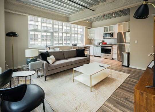 a living room with a couch and a coffee table    and a kitchen