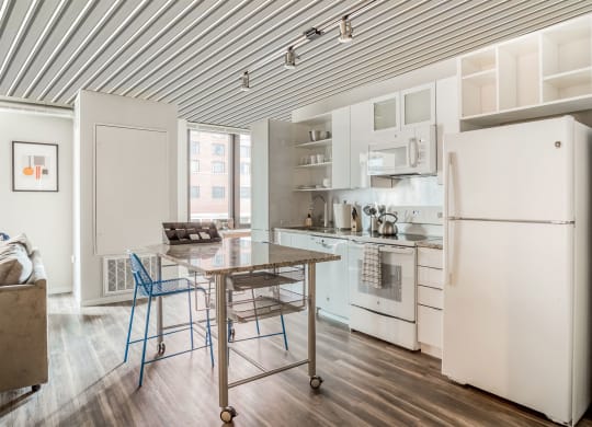 a kitchen with white appliances and a table with two stools