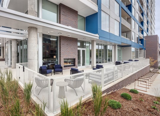 an outdoor patio with chairs and a fireplace at an apartment building