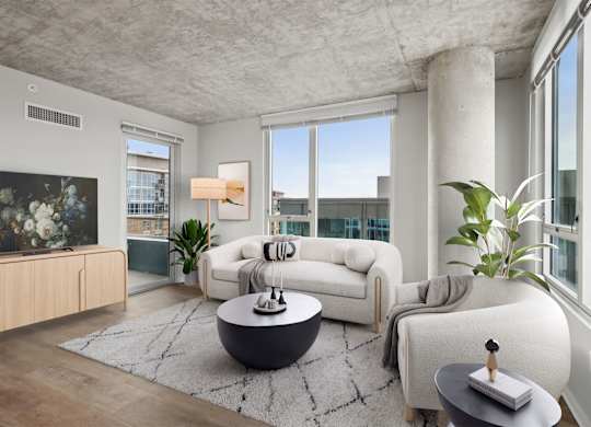 A modern living room with a white sofa, a black coffee table, and a large window.