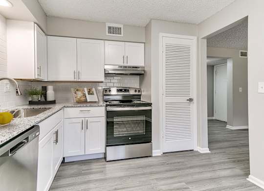 A kitchen with white cabinets and a stainless steel oven.
