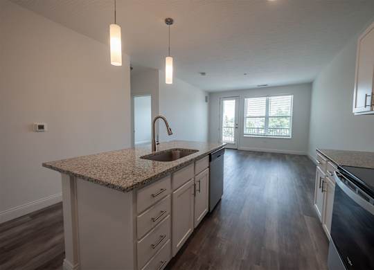 A kitchen with a granite countertop and wooden floors.