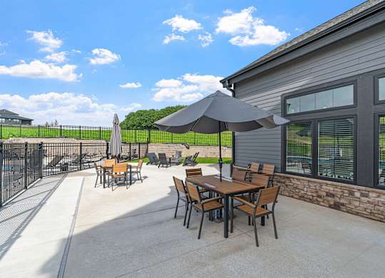 A patio with a table and chairs and a black umbrella.