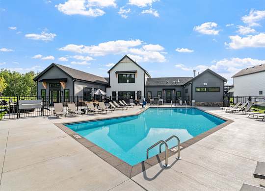 A swimming pool in front of a building with a sunny sky.