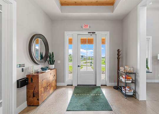 A white hallway with a green rug and a mirror on the wall.