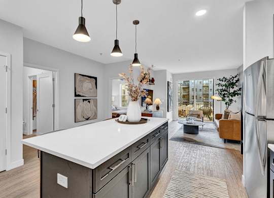 A modern kitchen with a large island and pendant lights.