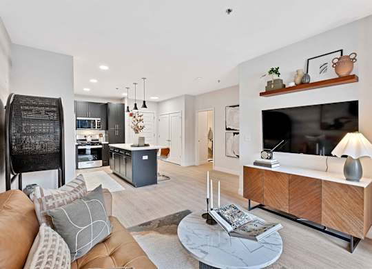 A modern living room with a brown leather couch and a wooden entertainment center.
