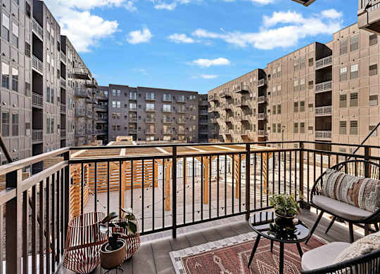 A balcony with a table and chairs overlooks a courtyard.