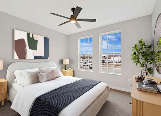 A bedroom with a bed, nightstands, a ceiling fan, and a painting on the wall.