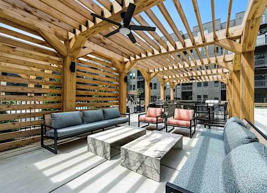 A wooden pergola with a bench and a table is in the foreground.