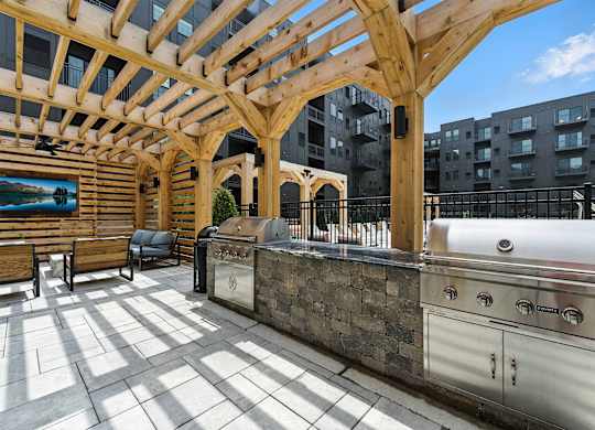 A wooden pergola over a barbecue grill on a patio.