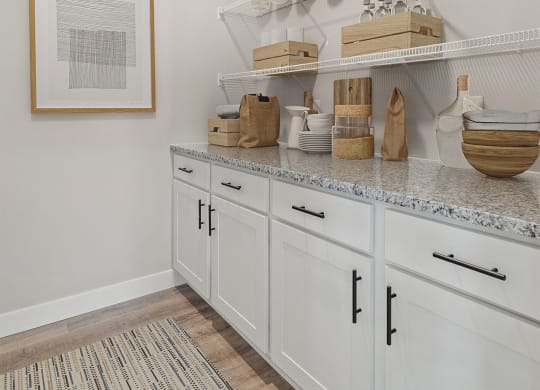 a kitchen with white cabinets and baskets and baskets on shelves