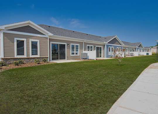 A row of houses with a sidewalk in front.