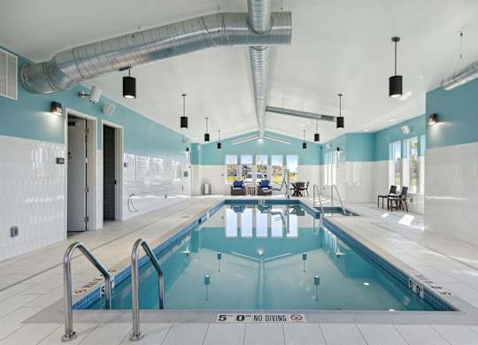 A large indoor swimming pool with a diving board and a sign that says