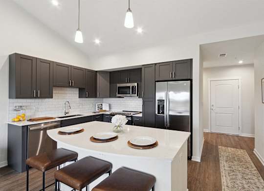 A kitchen with a white island and brown stools.