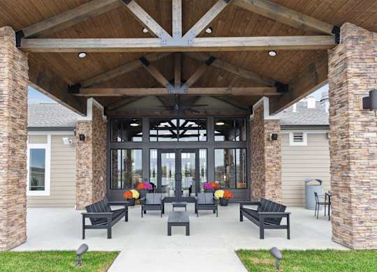 A covered patio with black furniture and pillows.