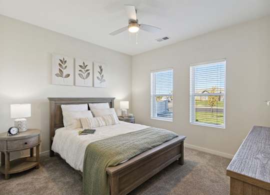 A bedroom with a bed, nightstand, and a fan.
