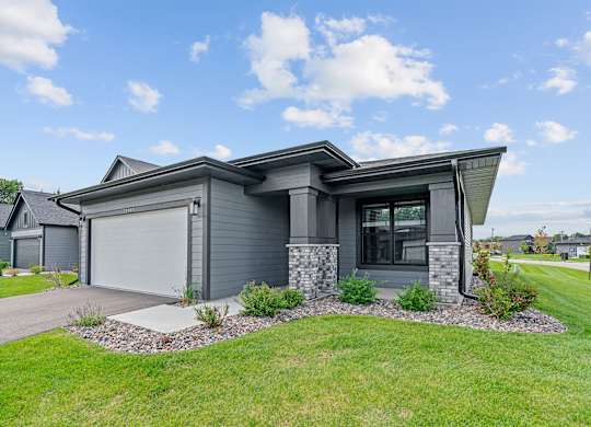 A modern house with a grey exterior and a stone pillar.
