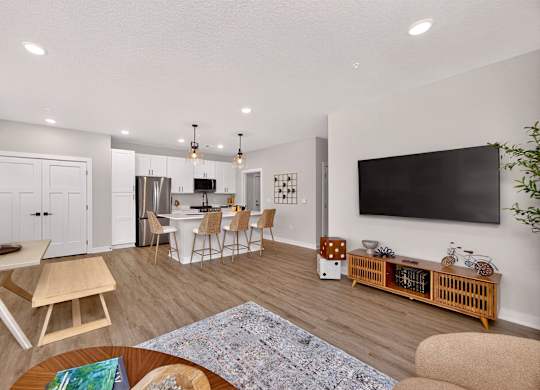 A modern living room with a dining area and a kitchen in the background.