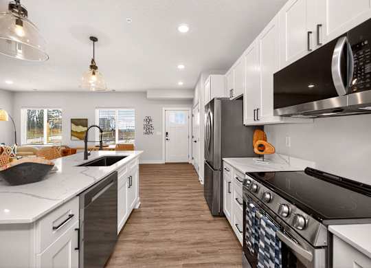 A modern kitchen with white cabinets and black appliances.
