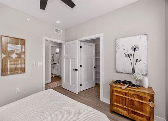 A bedroom with a bed, dresser, and artwork.