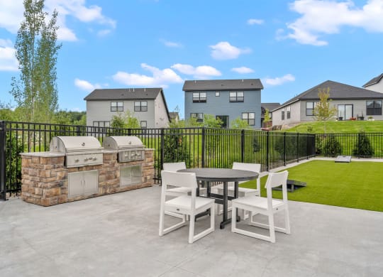 a patio with a table and chairs and a grill