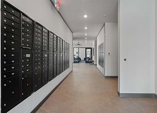 A long hallway with black mailboxes on the wall.