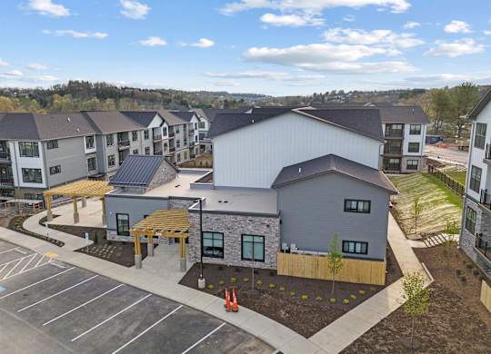 A parking lot is in front of a building with a grey roof.