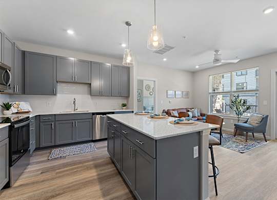 A modern kitchen with a large island and grey cabinets.