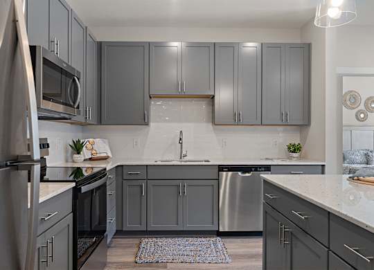 A kitchen with grey cabinets and a white countertop.