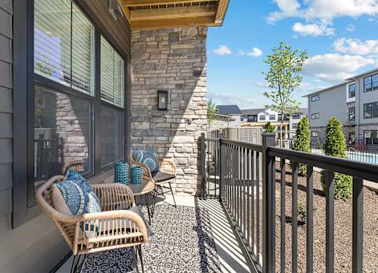 A patio with a wicker chair and a stone pillar.
