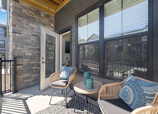 A patio with a chair and a table with a blue cushion.