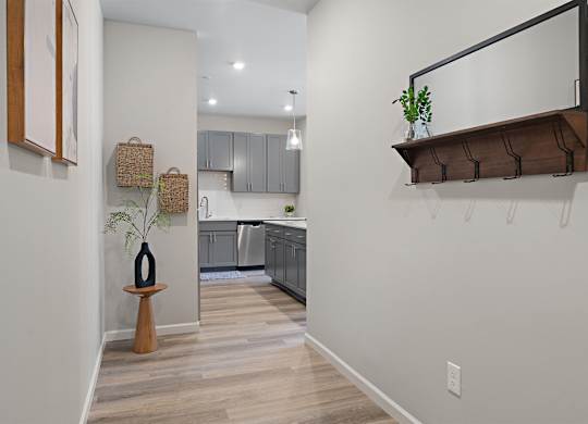 A kitchen with a white wall and a wooden floor.