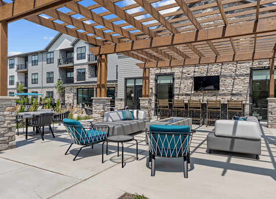 A patio with a stone wall and a wooden pergola.
