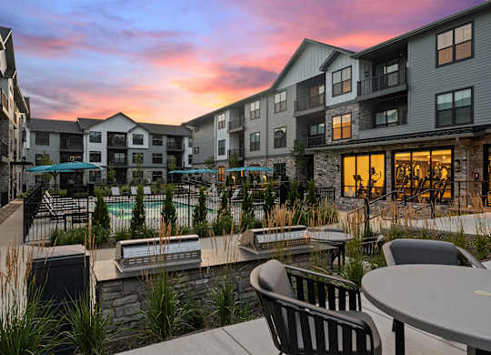 A sunset view of a resort with a pool and chairs.