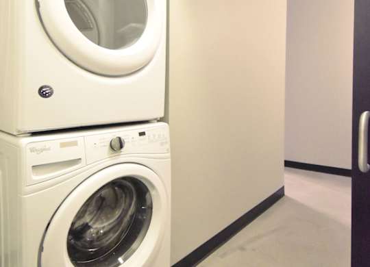 Two white front loading washing machines stacked on top of each other.